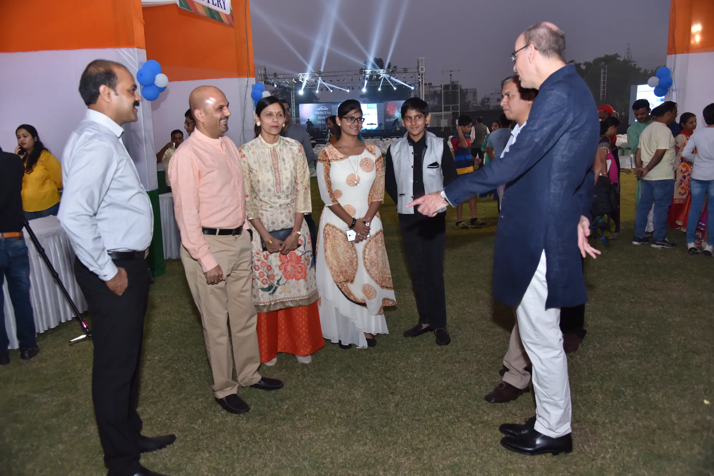 Men lighting ceremonial lamp at event with ITT banner in background